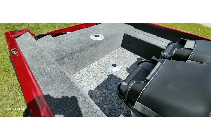 Slide: The Image of 2025 Tracker Super Guide V-16 SC boat interior with gray carpet and black seats. - 5