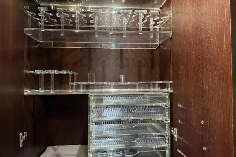 Slide: The Image of Clear acrylic storage shelves inside a wooden cabinet on a 2005 Mangusta 92 yacht. - 16