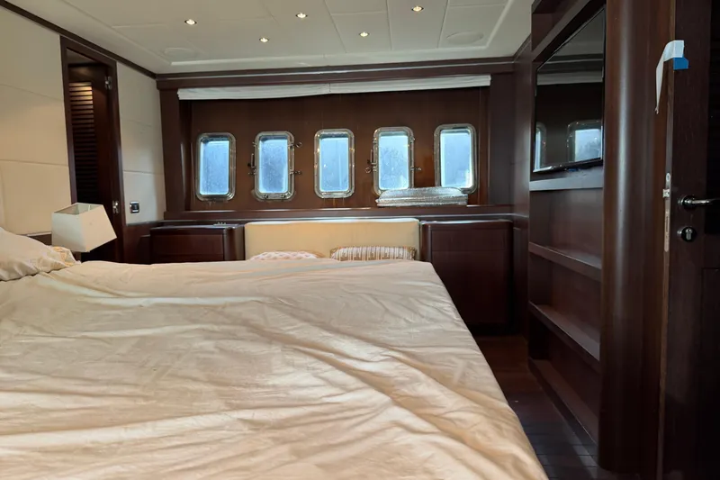 Slide: The Image of Luxurious bedroom interior of 2005 Mangusta 92 yacht with wooden accents and porthole windows. - 31