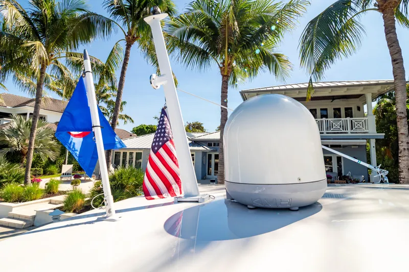 Slide: The Image of 2016 Intrepid 400 Cuddy yacht with flags, palm trees, and a modern house in the background. - 120