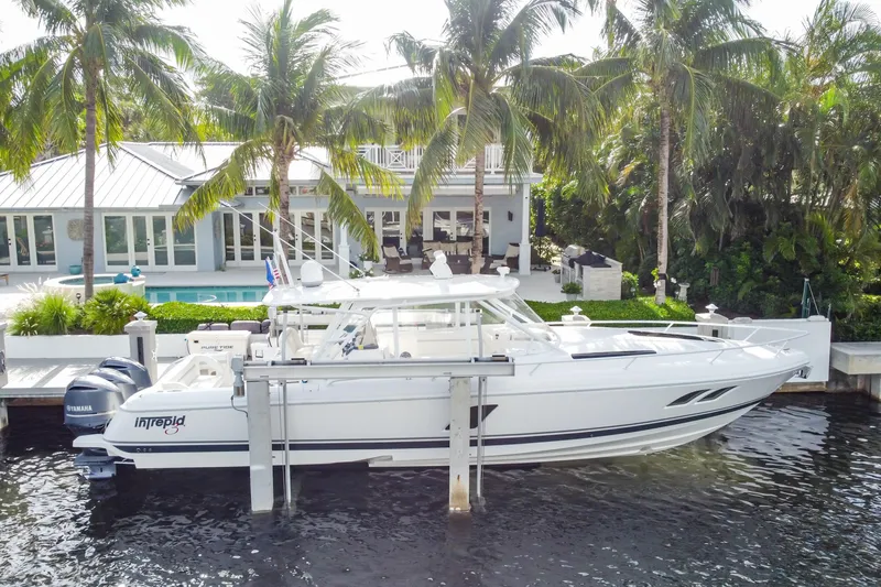 Slide: The Image of 2016 Intrepid 400 Cuddy boat docked by a waterfront home with palm trees. - 13