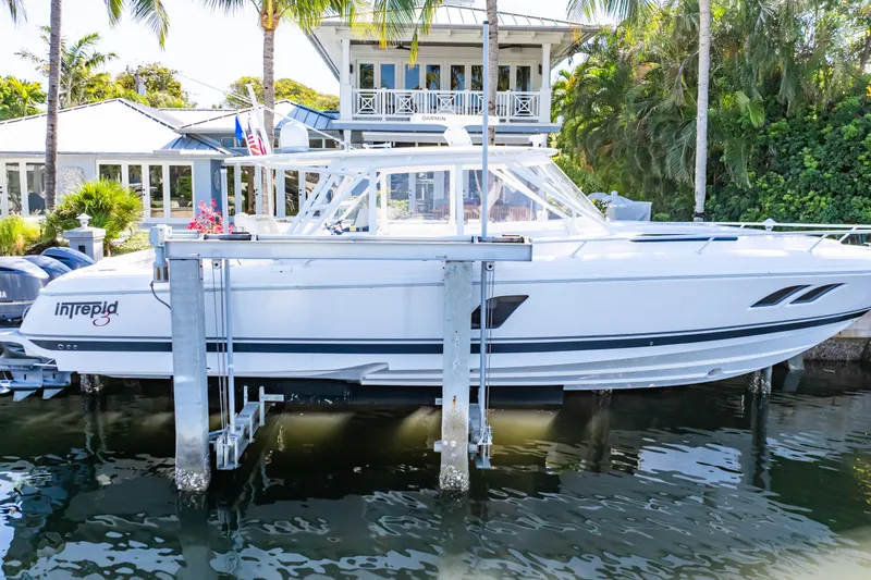 Slide: The Image of 2016 Intrepid 400 Cuddy boat docked near a waterfront home with lush greenery. - 138