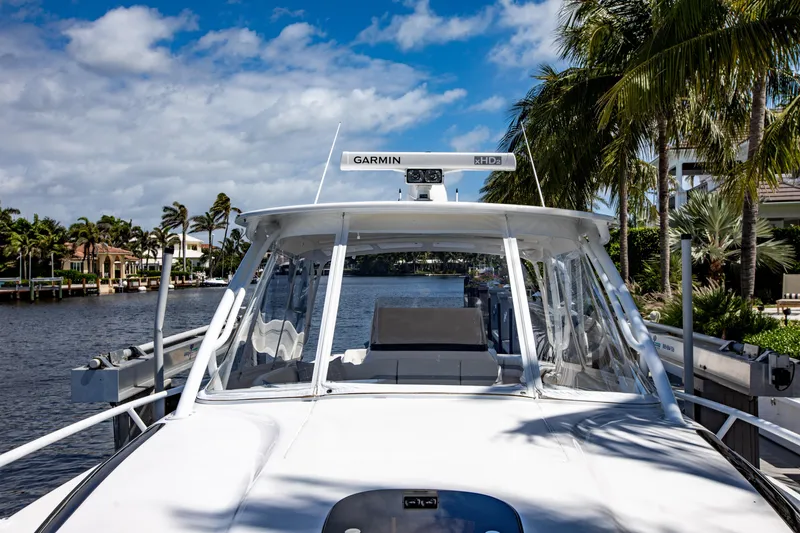 Slide: The Image of 2016 Intrepid 400 Cuddy boat docked by palm trees and waterfront homes. - 39