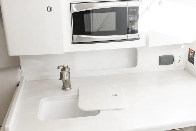 Slide: The Image of 2016 Intrepid 400 Cuddy kitchenette with sink, faucet, and built-in microwave. - 70