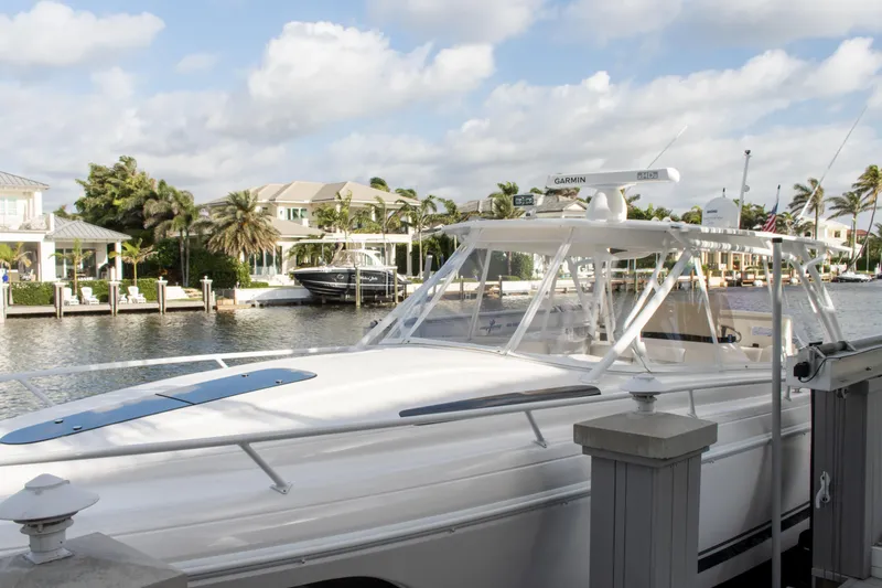 Slide: The Image of 2016 Intrepid 400 Cuddy boat docked by waterfront homes under a cloudy sky. - 72