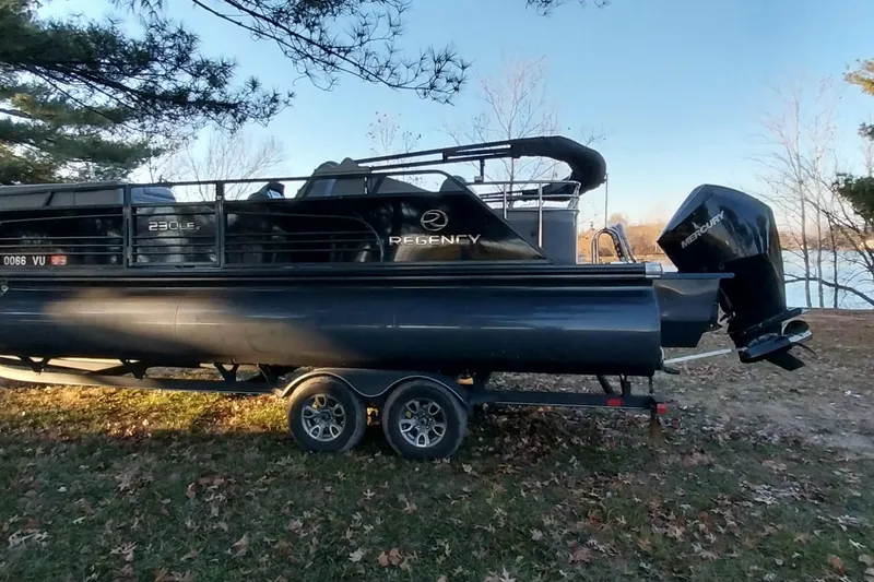 Slide: The Image of 2021 Regency 230 LE3 Sport pontoon boat on trailer by lakeside in autumn setting. - 11