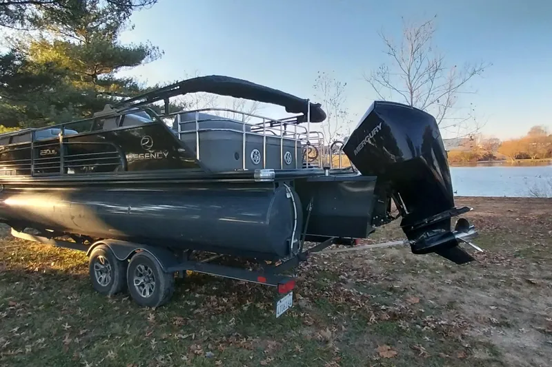 Slide: The Image of 2021 Regency 230 LE3 Sport pontoon boat on trailer by a lake. - 12