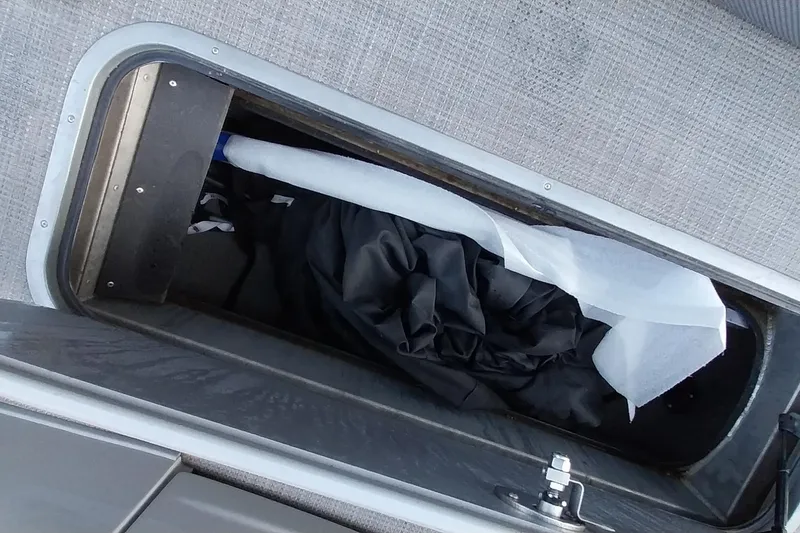 Slide: The Image of Storage compartment in a 2021 Regency 230 LE3 Sport boat, containing fabric and a white roll. - 25