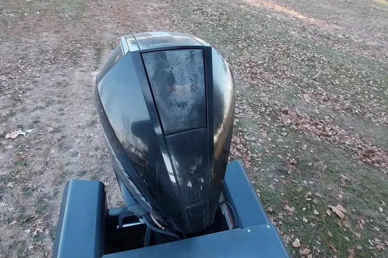 Slide: The Image of Outboard motor on a 2021 Regency 230 LE3 Sport boat, parked on grassy terrain. - 31