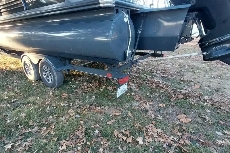 Slide: The Image of 2021 Regency 230 LE3 Sport boat on trailer, parked on grassy area with fallen leaves. - 6