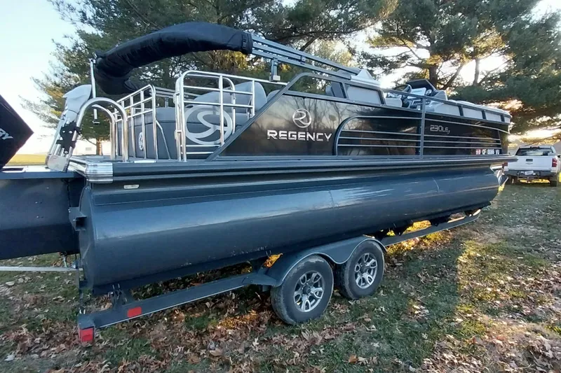 Slide: The Image of 2021 Regency 230 LE3 Sport pontoon boat on trailer, parked outdoors. - 8