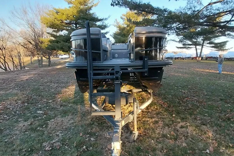 Slide: The Image of 2021 Regency 230 LE3 Sport pontoon boat on trailer in a wooded area. - 9