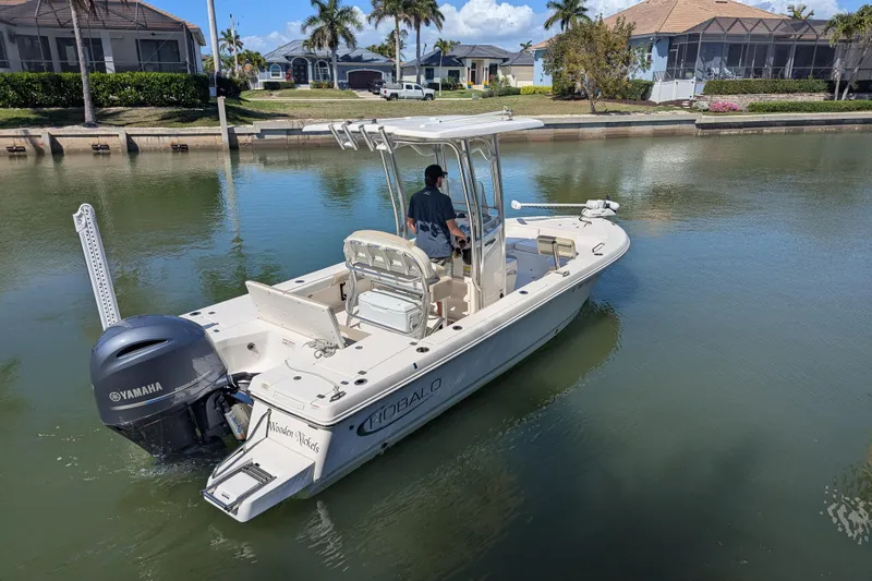 Slide: The Image of 2021 Robalo 226 Cayman boat cruising in a calm residential canal. - 2