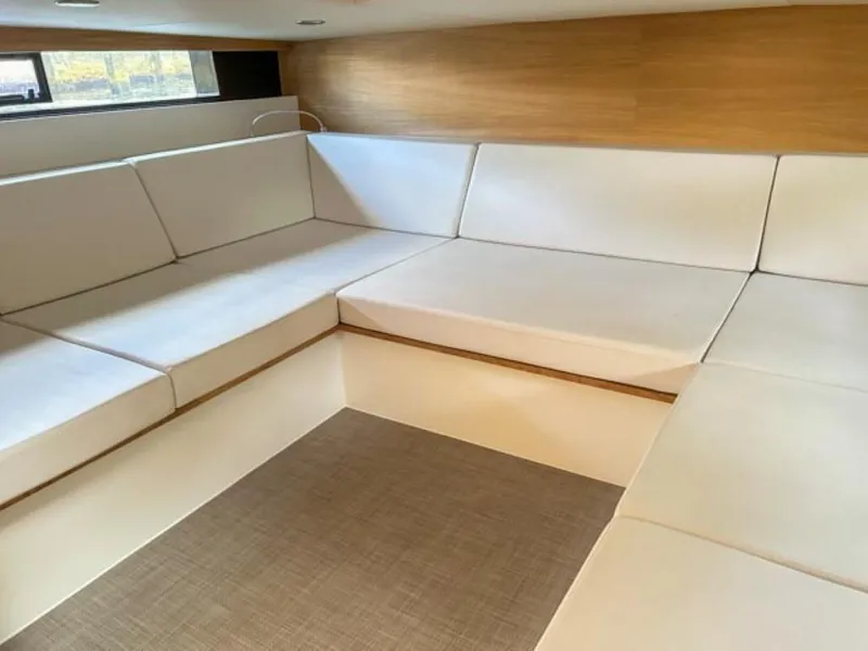 Slide: The Image of Interior seating area of 2023 De Antonio Yachts D42 Open with white cushions and wooden accents. - 17