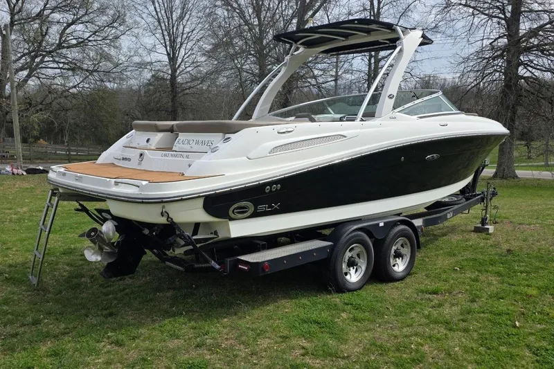 Slide: The Image of 2011 Sea Ray SLX 250 boat on trailer, parked on grass with trees in background. - 3