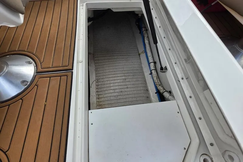 Slide: The Image of 2011 Sea Ray SLX 250 boat storage compartment with teak flooring and visible piping. - 30