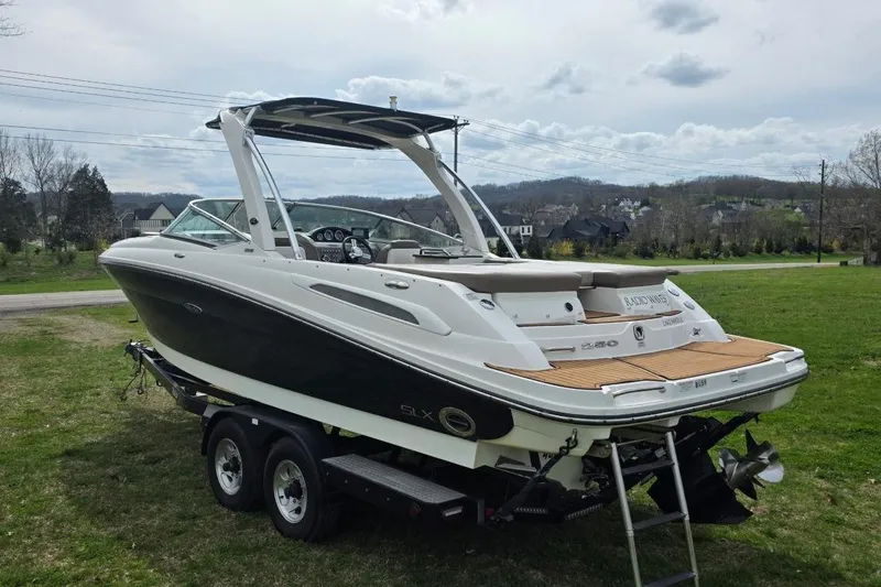 Slide: The Image of 2011 Sea Ray SLX 250 boat on trailer, parked on grass with scenic background. - 7