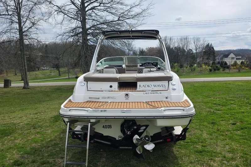 Slide: The Image of 2011 Sea Ray SLX 250 boat on grass, rear view with ladder and propeller visible. - 8