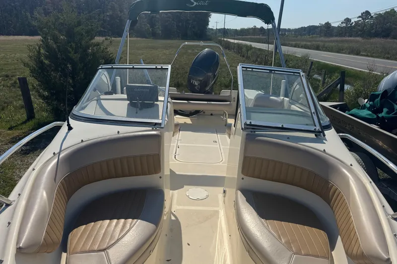 Slide: The Image of 2004 Scout 175 Dorado boat with tan seating and windshield, parked near a road. - 11