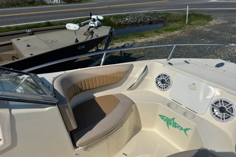 Slide: The Image of 2004 Scout 175 Dorado boat interior with seating and speakers, parked near a road. - 9