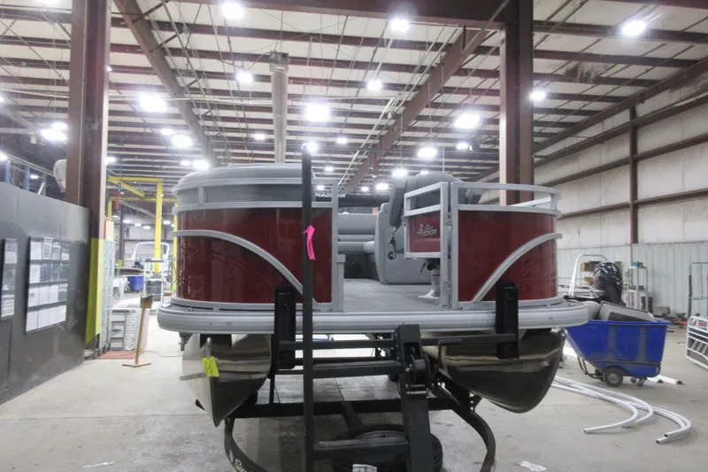 Slide: The Image of 2026 Sun Tracker SportFish 20 DLX pontoon boat in a factory setting. - 2