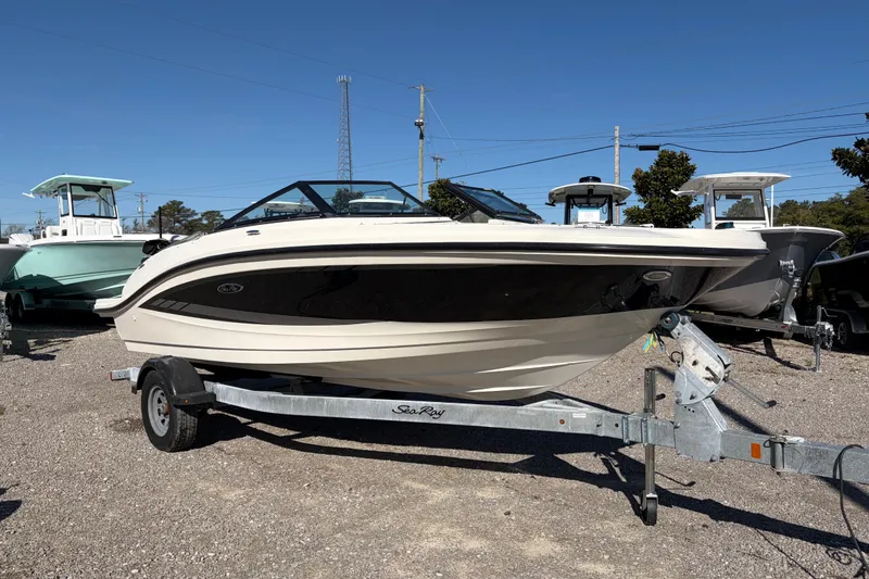 Slide: The Image of 2015 Sea Ray 19 SPX boat on trailer, parked outdoors under clear blue sky. - 6