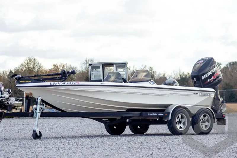 The Image of 2000 Champion 193 CX boat on trailer with Mercury engine, parked outdoors. - 1