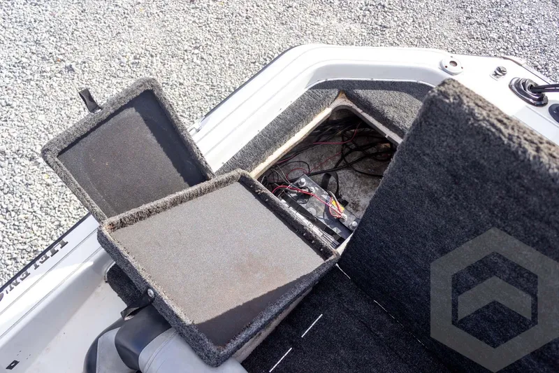 Slide: The Image of Open storage compartment in a 2000 Champion 193 CX boat, revealing wiring and battery. - 39