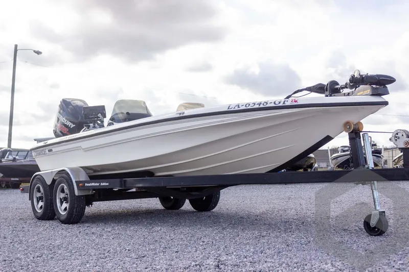 Slide: The Image of 2000 Champion 193 CX boat on trailer, featuring Mercury engine, parked on gravel. - 6