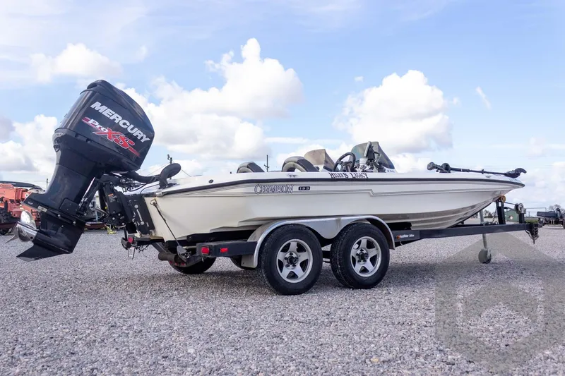Slide: The Image of 2000 Champion 193 CX boat with Mercury engine on a trailer, parked on gravel. - 8
