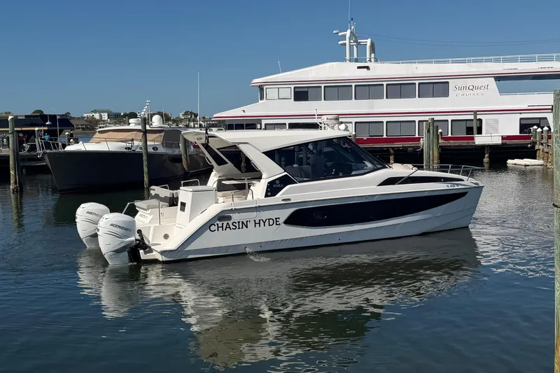 The Image of 2023 Aquila 36 Sport boat docked in marina with cruise ship in background. - 0