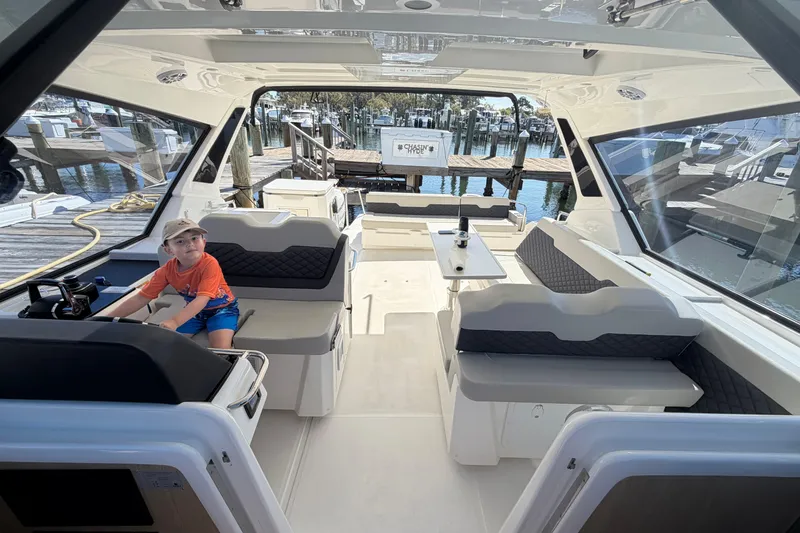 Slide: The Image of 2023 Aquila 36 Sport interior with seating and a child at the helm. - 14