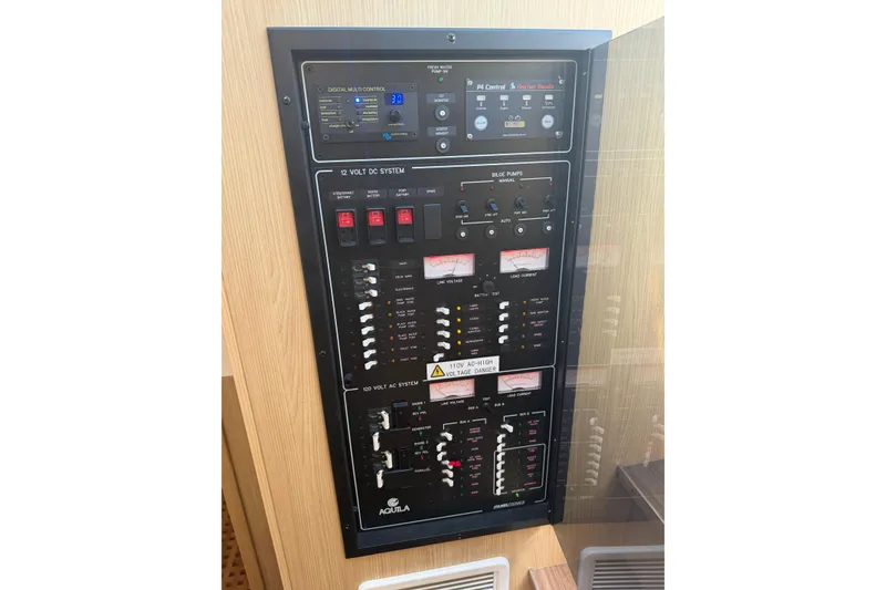 Slide: The Image of Electrical control panel on a 2023 Aquila 36 Sport boat, featuring various switches and gauges. - 28