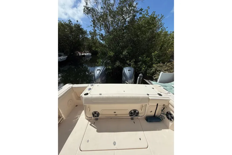 Slide: The Image of 2021 Grady-White Canyon 336 boat with dual engines, docked near lush greenery. - 17