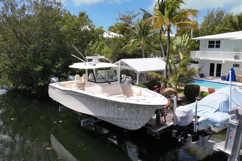 Slide: The Image of 2021 Grady-White Canyon 336 boat docked near tropical home with pool. - 2