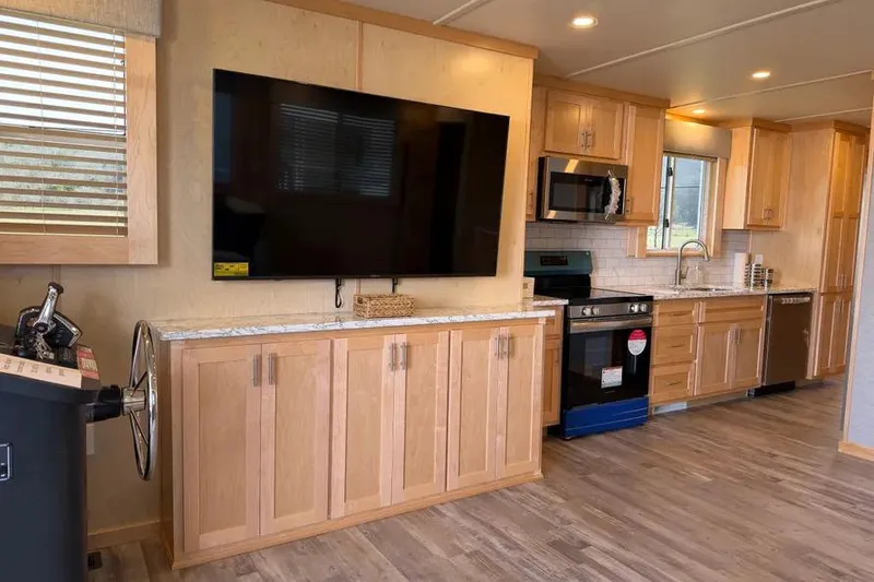 Slide: The Image of Modern kitchen interior in 2026 Sumerset Voyager houseboat with wooden cabinets and large TV. - 3