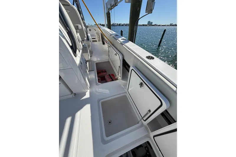 Slide: The Image of 2022 Invincible 40 Catamaran deck with open storage compartments, docked by the water. - 21