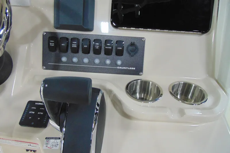 Slide: The Image of Control panel of 2026 Boston Whaler 220 Dauntless boat with switches and cup holders. - 17