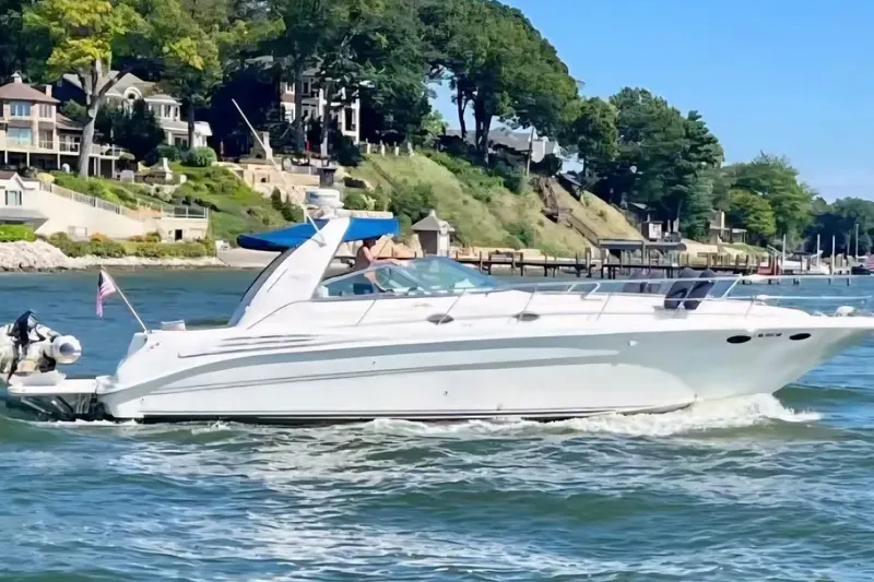 The Image of 1997 Sea Ray Sundancer 400 cruising on a scenic waterfront with luxury homes. - 0