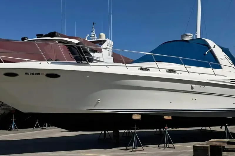 Slide: The Image of 1997 Sea Ray Sundancer 400 yacht on stands, with blue canopy, in a marina setting. - 3