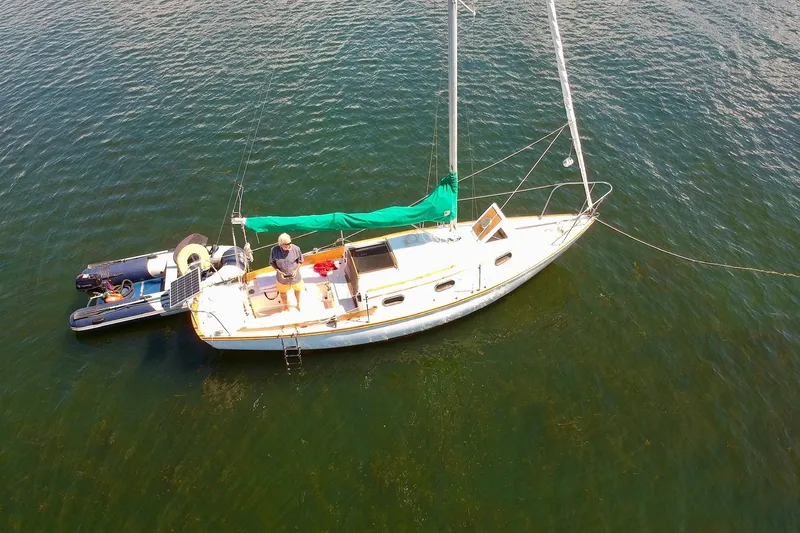 Slide: The Image of 1981 Cape Dory 25 sailboat with green sail cover on calm water. - 2