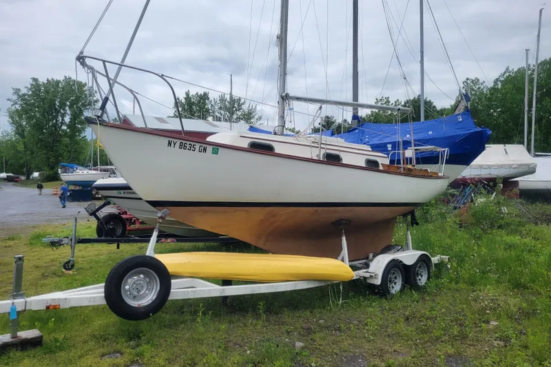 Slide: The Image of 1981 Cape Dory 25 sailboat on trailer, parked outdoors with lush greenery background. - 23