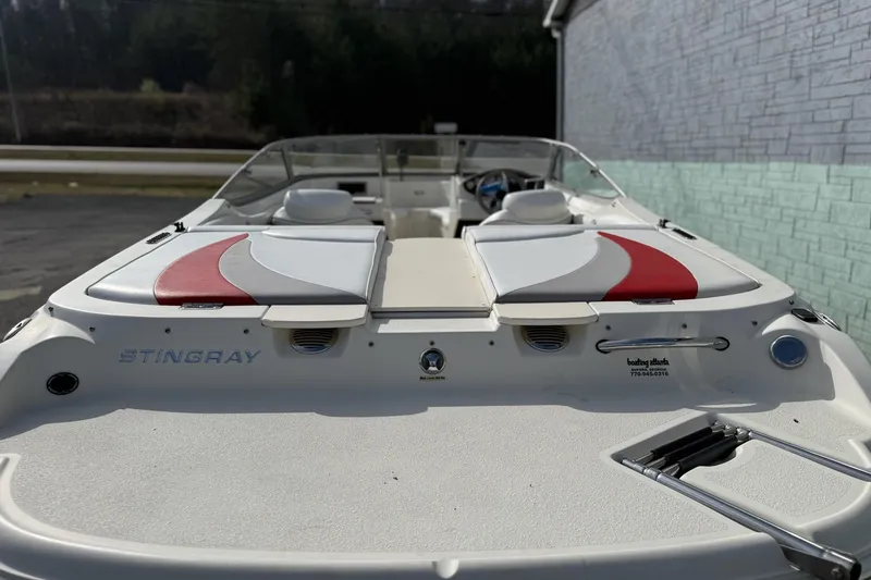 Slide: The Image of 2008 Stingray 205 LS/LX/LR boat with red and white seating, docked outdoors. - 4