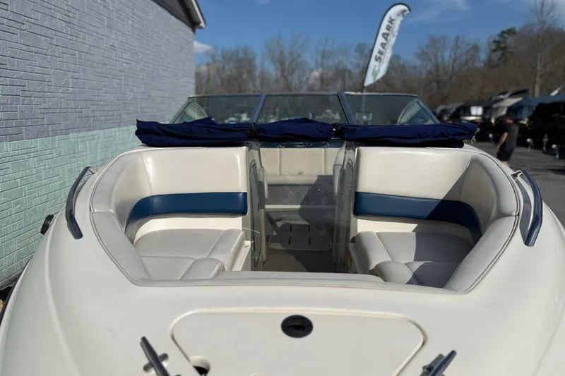 Slide: The Image of 1998 Bryant 214 Limited boat with white and blue interior, parked outdoors. - 3