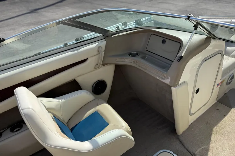Slide: The Image of Interior of a 1998 Bryant 214 Limited boat, featuring beige seating and dashboard. - 9