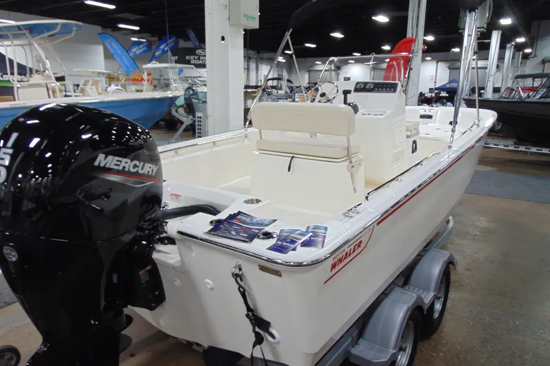 Slide: The Image of 2026 Boston Whaler 190 Montauk boat with Mercury engine on display indoors. - 2