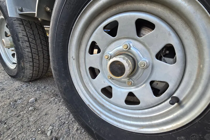 Slide: The Image of Close-up of 2020 Avalon LSZ VRB - 24' trailer wheel on gravel surface. - 16
