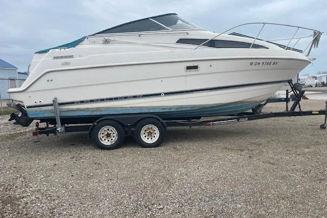 Slide: The Image of 1997 Bayliner 2355 boat on trailer, parked on gravel, side view. - 3