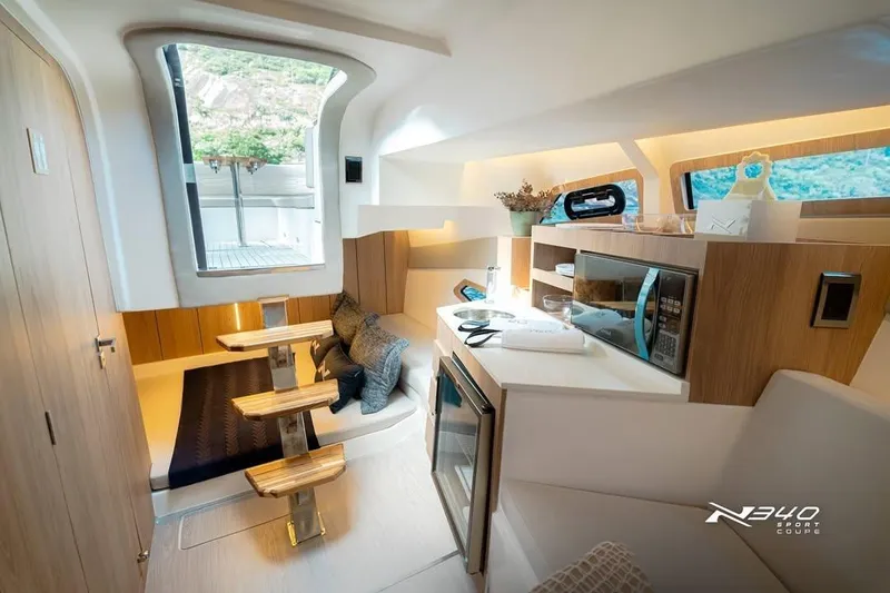 Slide: The Image of Interior of 2026 NX Boats NX340, featuring modern kitchen and cozy seating area. - 7