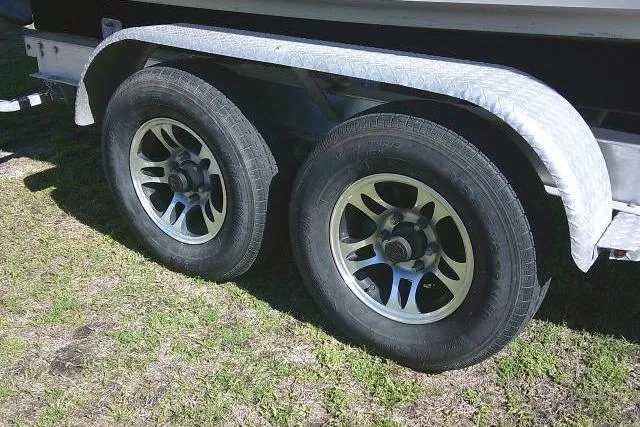 Slide: The Image of Trailer wheels of a 2017 Sailfish 240 CC boat on grass. - 12